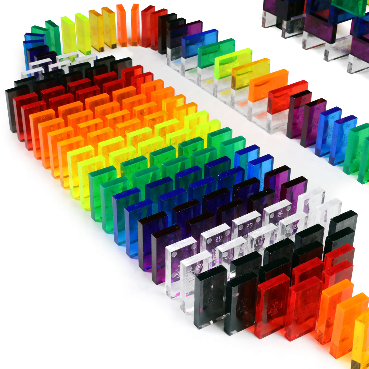 Bulk Dominoes Artisan Kit close-up of clear assorted Pro Dominoes standing in rows showing translucent rainbow colors including red, orange, yellow, green, blue, purple, and clear