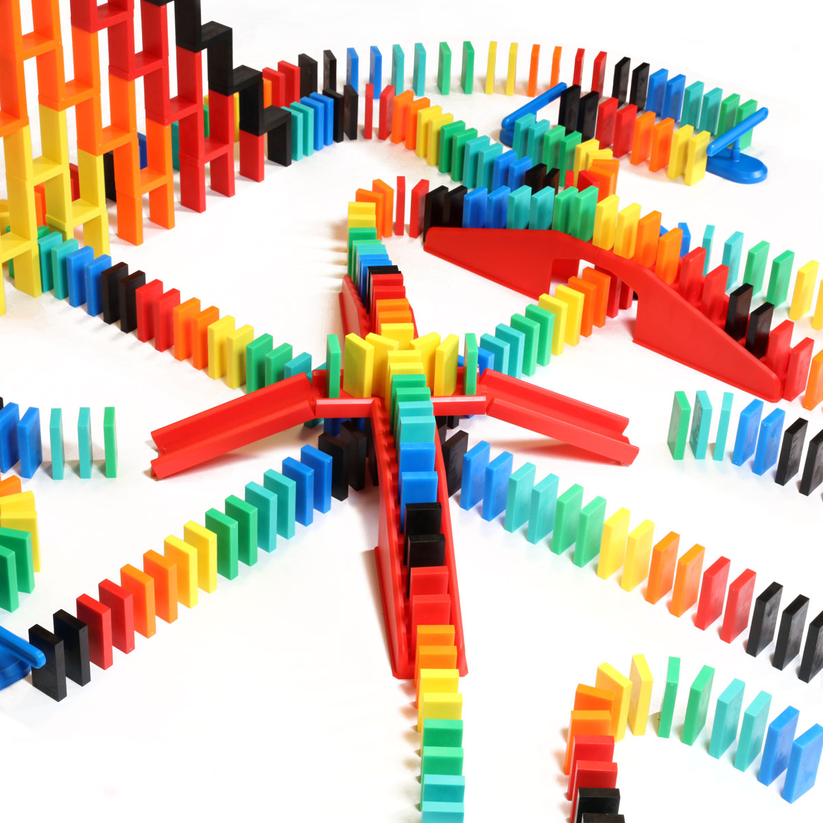 Close-up of the Bulk Dominoes Expert Kit showing rainbow Pro Dominoes flowing across red bridges in an elaborate chain reaction layout from Atwood Toys.