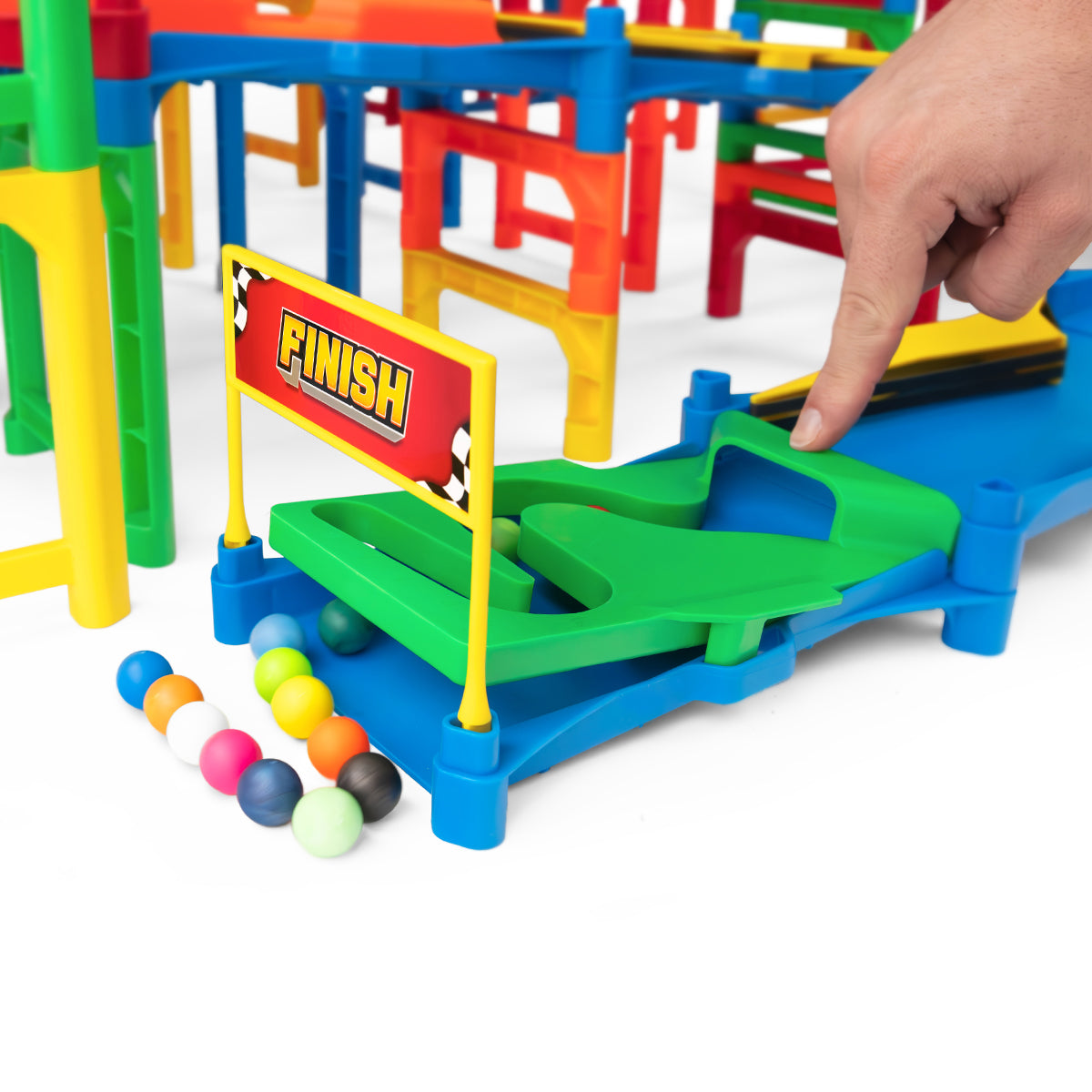 IMR Grand Prix Overdrive finish line gate with hand placing marble on green track and colorful marbles collected at the base