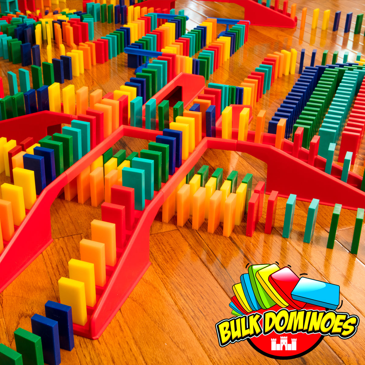 Bulk Dominoes Master Builder Kit close-up on hardwood floor showing colorful Pro Dominoes lined up on red straight tracks and bridges with multiple chain reaction paths crossing and intersecting
