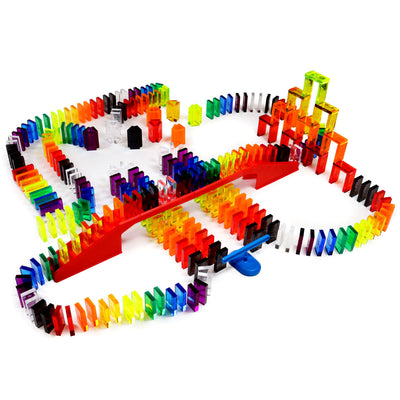 Bulk Dominoes Artisan Kit alternate chain reaction layout with clear rainbow dominoes, red bridge, blue spinner accessory, and stacked 3D domino tower