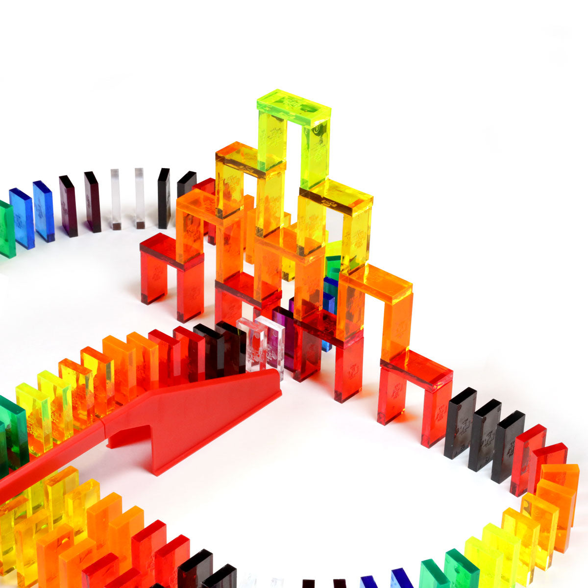 Bulk Dominoes Artisan Kit close-up of clear translucent dominoes stacked into a 3D tower structure with red bridge and rainbow-colored domino chain curving around the base