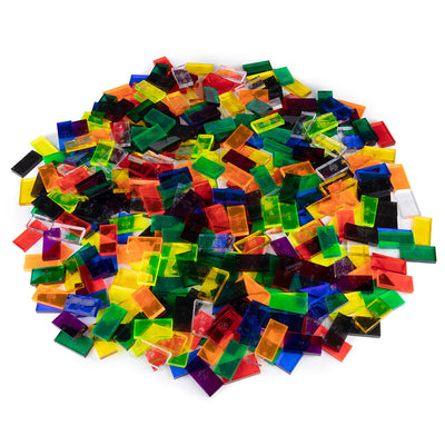 Bulk Dominoes Clear Assorted Colors Pro Dominoes from Atwood Toys, a top-down pile of translucent full-weight toppling dominoes in red, orange, yellow, green, blue, and purple for chain reactions and domino art.