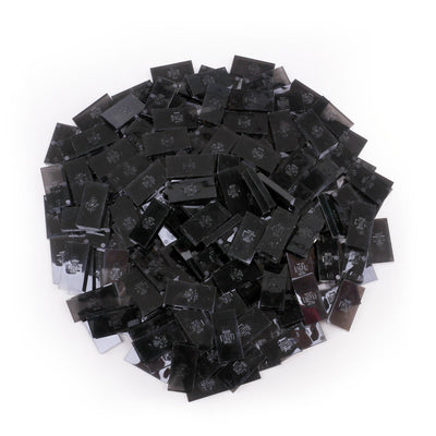 Bulk Dominoes Clear Smoke Pro Dominoes from Atwood Toys, a top-down pile of translucent smoke gray full-weight toppling dominoes for chain reactions and domino art.