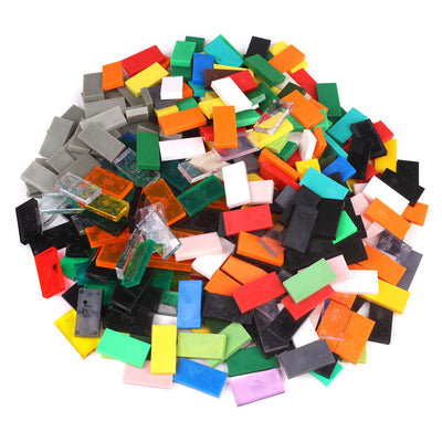 Bulk Dominoes closeout dominoes 100-piece pile showing a random mix of solid and clear Pro Dominoes in assorted colors including red, green, black, orange, white, and translucent