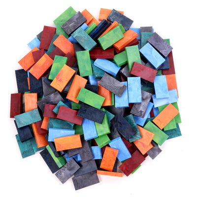 Bulk Dominoes Storm Mix Pro Dominoes from Atwood Toys, a top-down pile of marbled red, orange, green, teal, blue, navy, and black full-weight toppling dominoes for chain reactions and domino art.