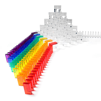 Bulk Dominoes Artisan Kit clear Pro Dominoes in rainbow chain curving toward a large 3D pyramid structure built from clear dominoes with domino template in background
