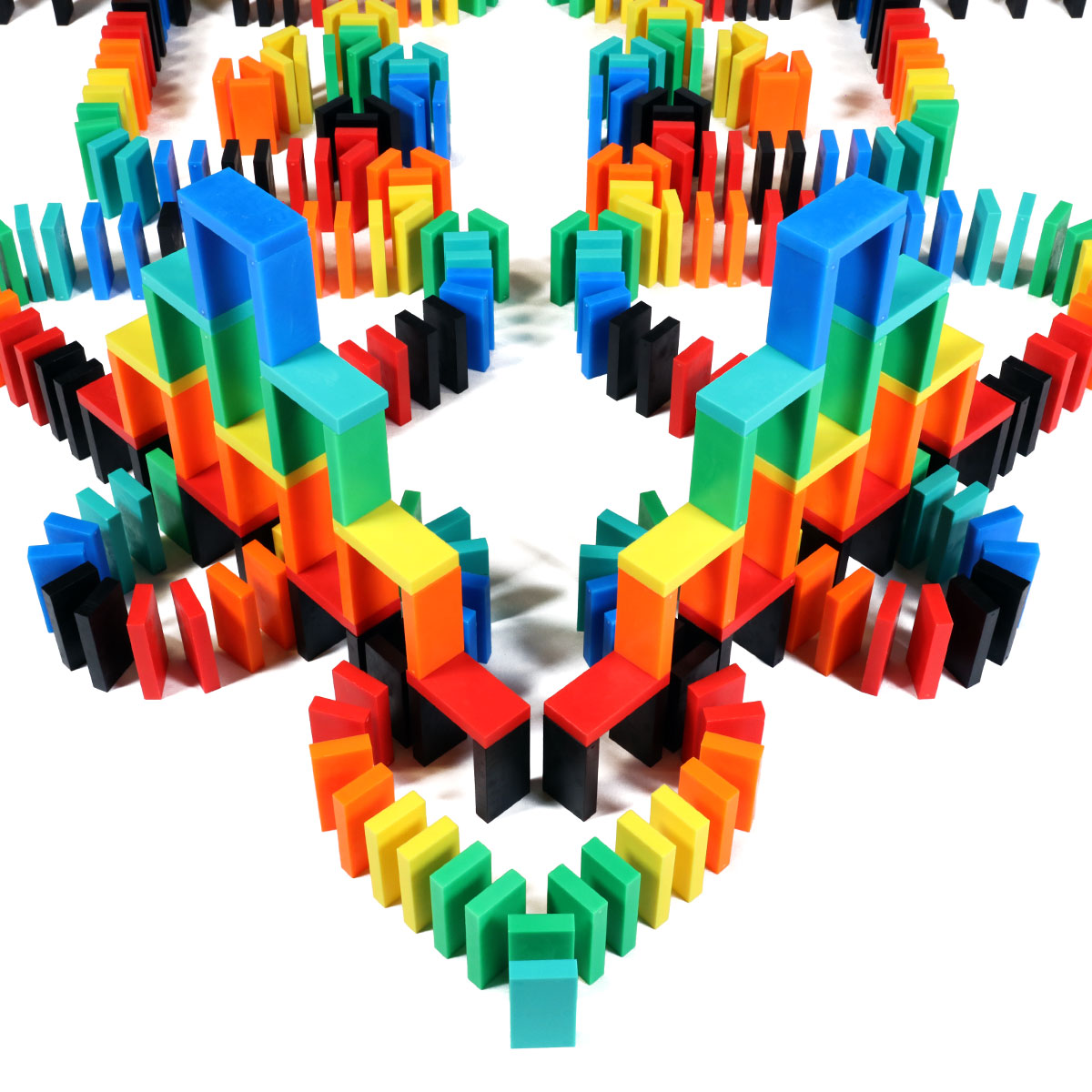 Multicolor 3D tower structure built from rainbow Bulk Dominoes Expert Kit Pro Dominoes in red, orange, yellow, green, blue, teal, and black, demonstrating advanced domino architecture.