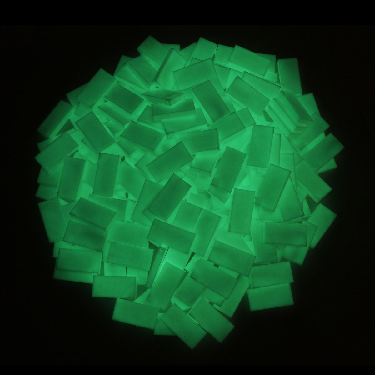 Top-down pile of Bulk Dominoes Glow-in-the-Dark Pro Dominoes shown in daylight in their pale off-white color before they charge up and glow.