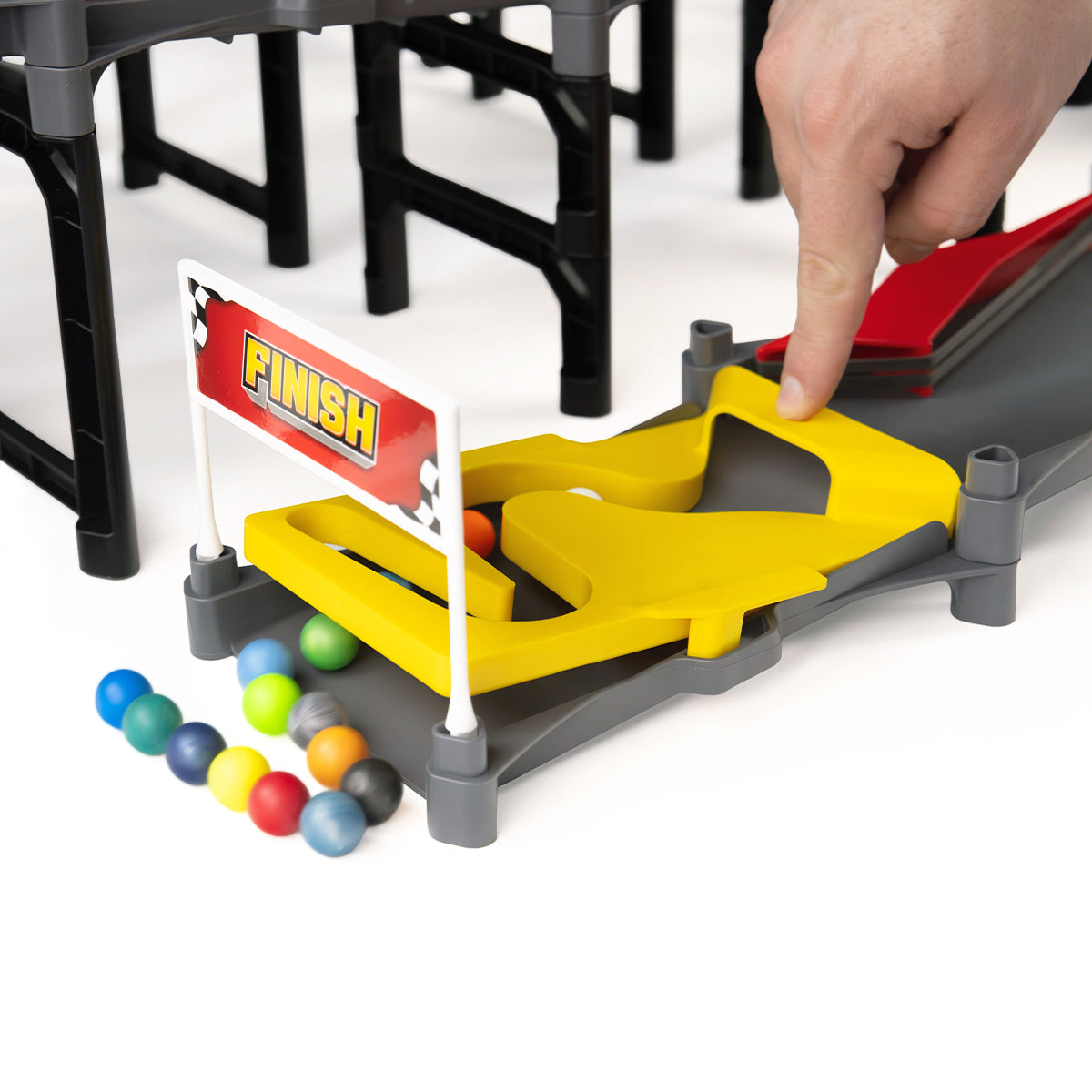 IMR Grand Prix Redline finish line gate close-up with hand placing marble on yellow track and colorful marbles collected below