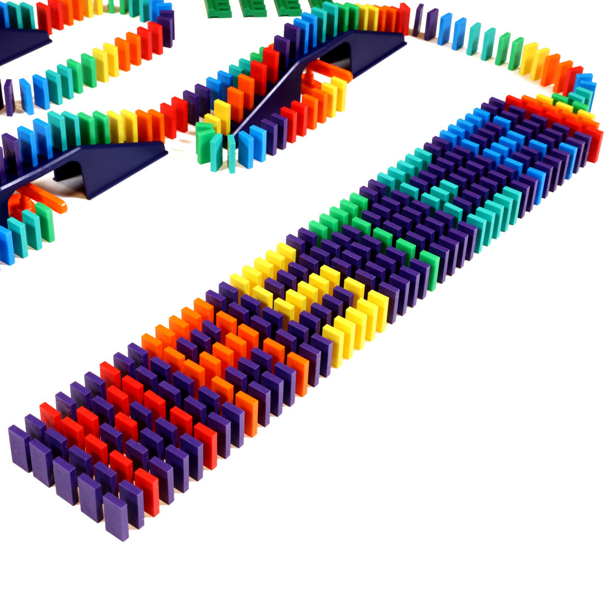 Close-up of the Bulk Dominoes Mini Master Kit showing rainbow Mini Dominoes lined up across navy blue bridges and ramps for chain reaction setups.