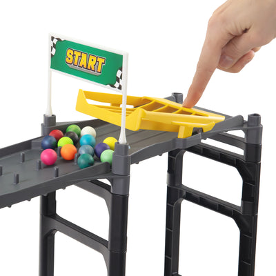 IMR Speedway Redline starting block with hand pressing yellow marble release gate, start flag, and colorful marbles loaded on elevated track