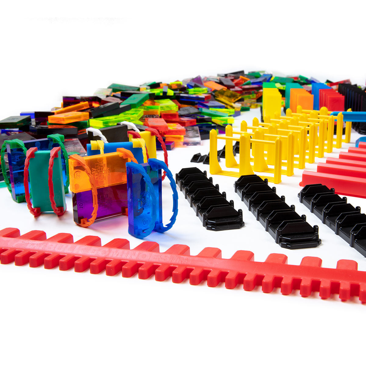 Atwood Toys Bulk Dominoes Super Mega Kit close-up of multi-color Domino Arcs, yellow line reactors, black bridges, red rapid tracks, and assorted clear dominoes