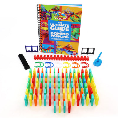 Bulk Dominoes Ultimate Starter Kit 101 contents laid out, including 100 colorful Kinetic Dominoes, support posts, kinetic clips, blue spinner, red speed template, and the Ultimate Guide to Domino Toppling book.