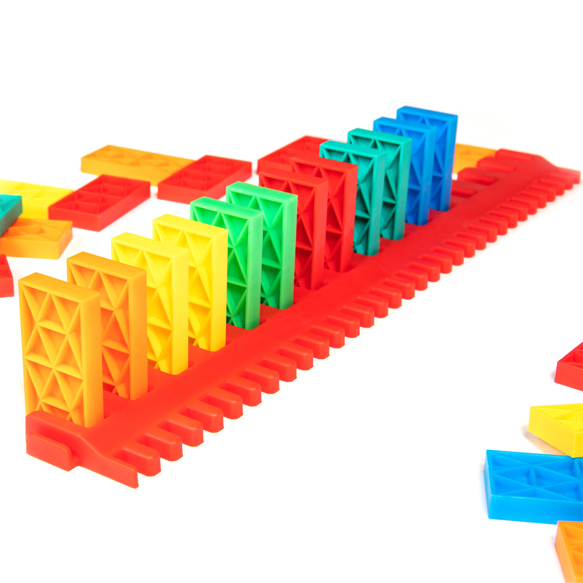 Bulk Dominoes Kinetic Speed Template in red holding a rainbow row of Kinetic Dominoes from the Ultimate Starter Kit 101, designed for fast domino setups.