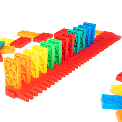 Bulk Dominoes Kinetic Speed Template in red holding a rainbow row of Kinetic Dominoes from the Ultimate Starter Kit 101, designed for fast domino setups.