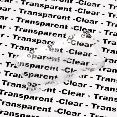 Bulk Dominoes Clear Pro Domino from Atwood Toys, a single transparent domino resting on text reading "Clear" and "Transparent" to demonstrate see-through clarity.