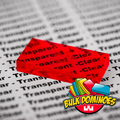 Close-up of a single translucent Bulk Dominoes Clear Red Pro Domino resting on printed text, with the words showing through to highlight its see-through clear finish.