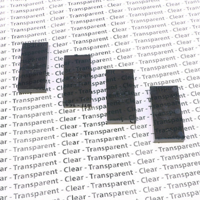Close-up of four translucent smoke gray Bulk Dominoes Clear Smoke Pro Dominoes from Atwood Toys lined up on a transparent and clear themed background.