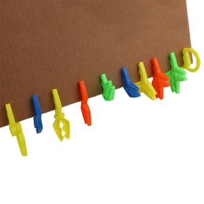 Multi-color Box Lox clips clipped in a row along the edge of a cardboard sheet to show how the connectors grip.